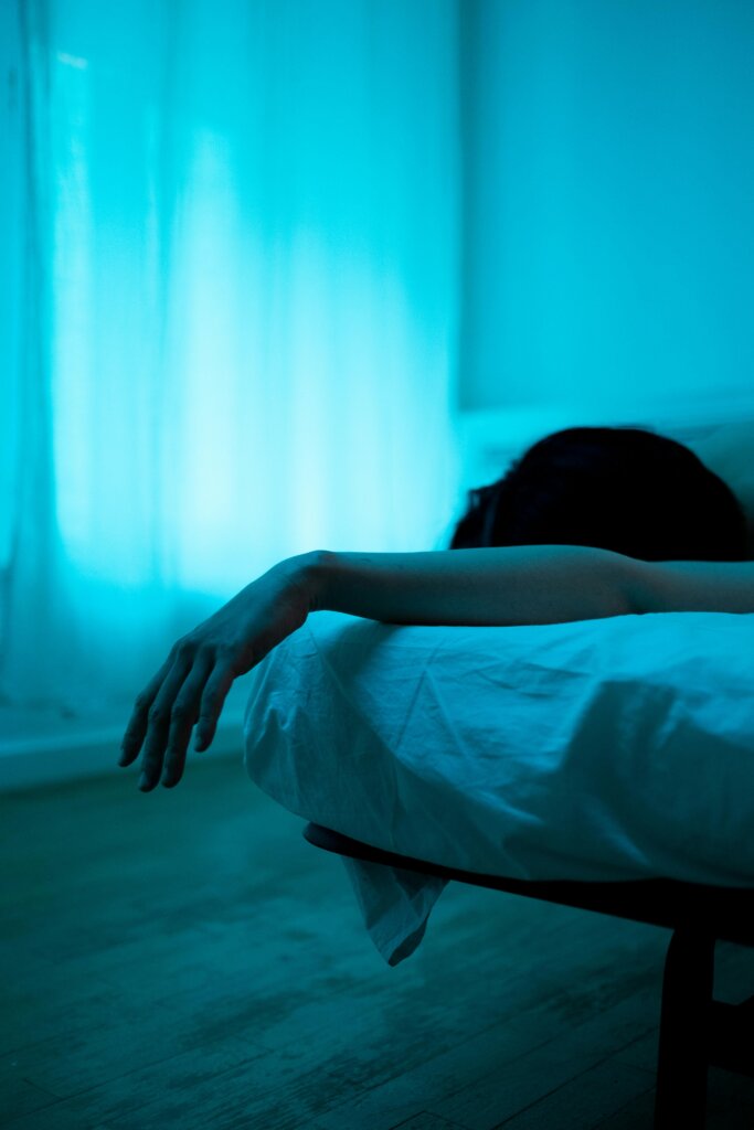 Person lying in bed bathed in soft blue light, suggesting quiet reflection and emotional stillness — a visual metaphor for insomnia relief and restful sleep.