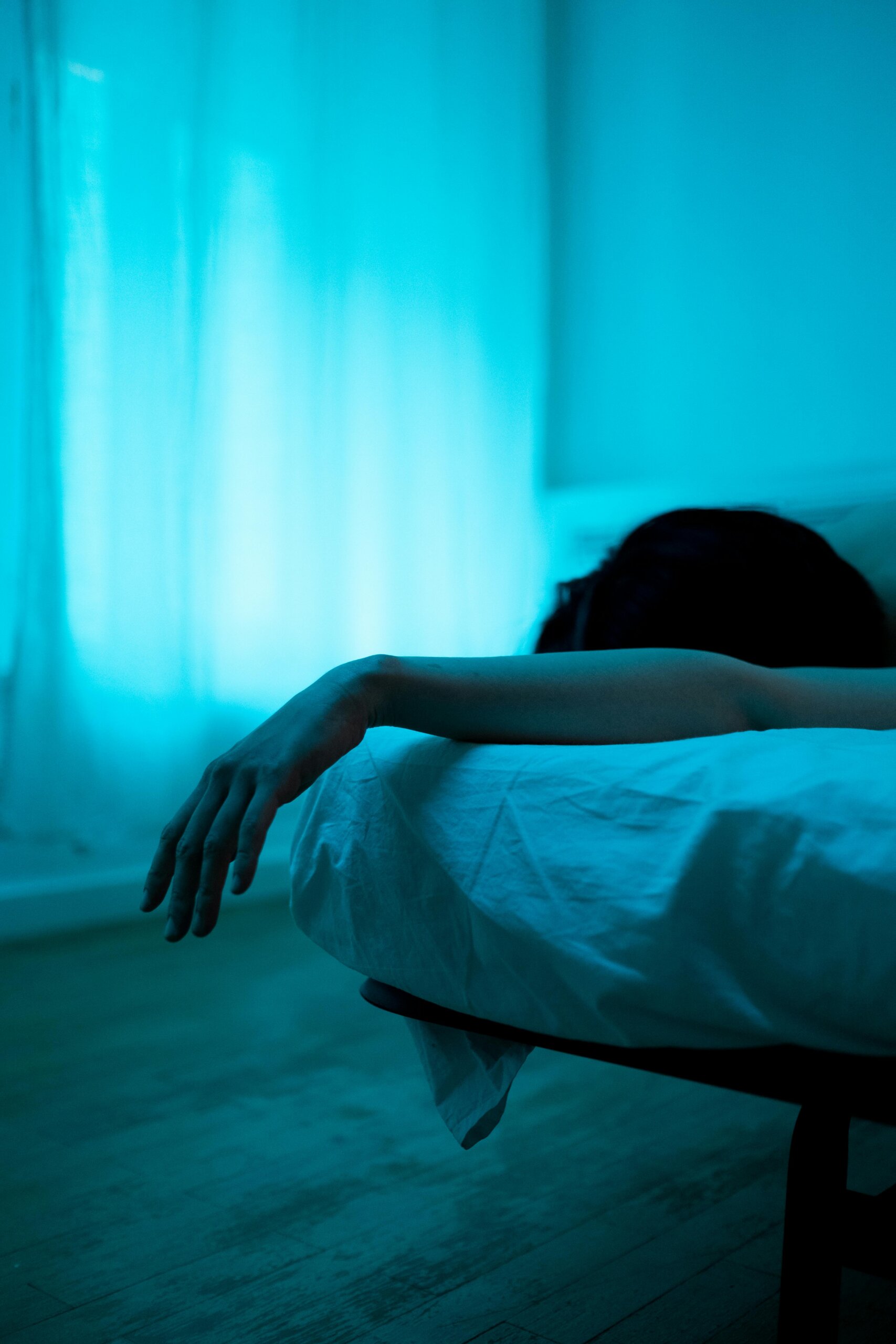 Person lying in bed bathed in soft blue light, suggesting quiet reflection and emotional stillness — a visual metaphor for insomnia relief and restful sleep.